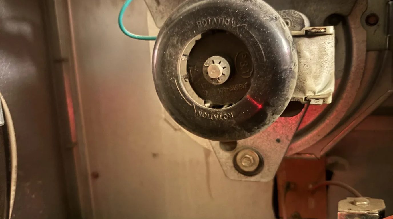 Close-up of a furnace inducer motor and housing inside a gas furnace cabinet