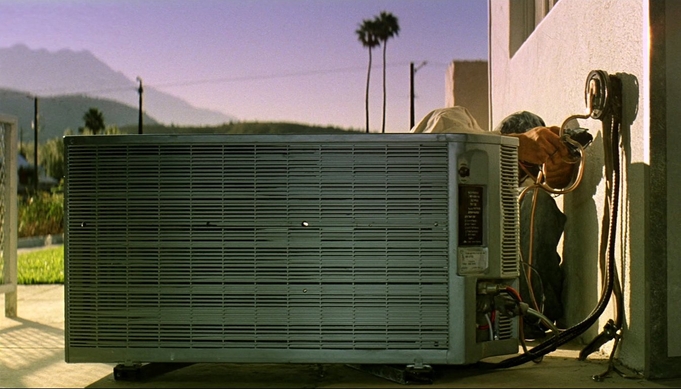 Outdoor AC condenser at a residential home in Rialto, California with palm trees and northern San Bernardino mountains - JC Energy Solutions