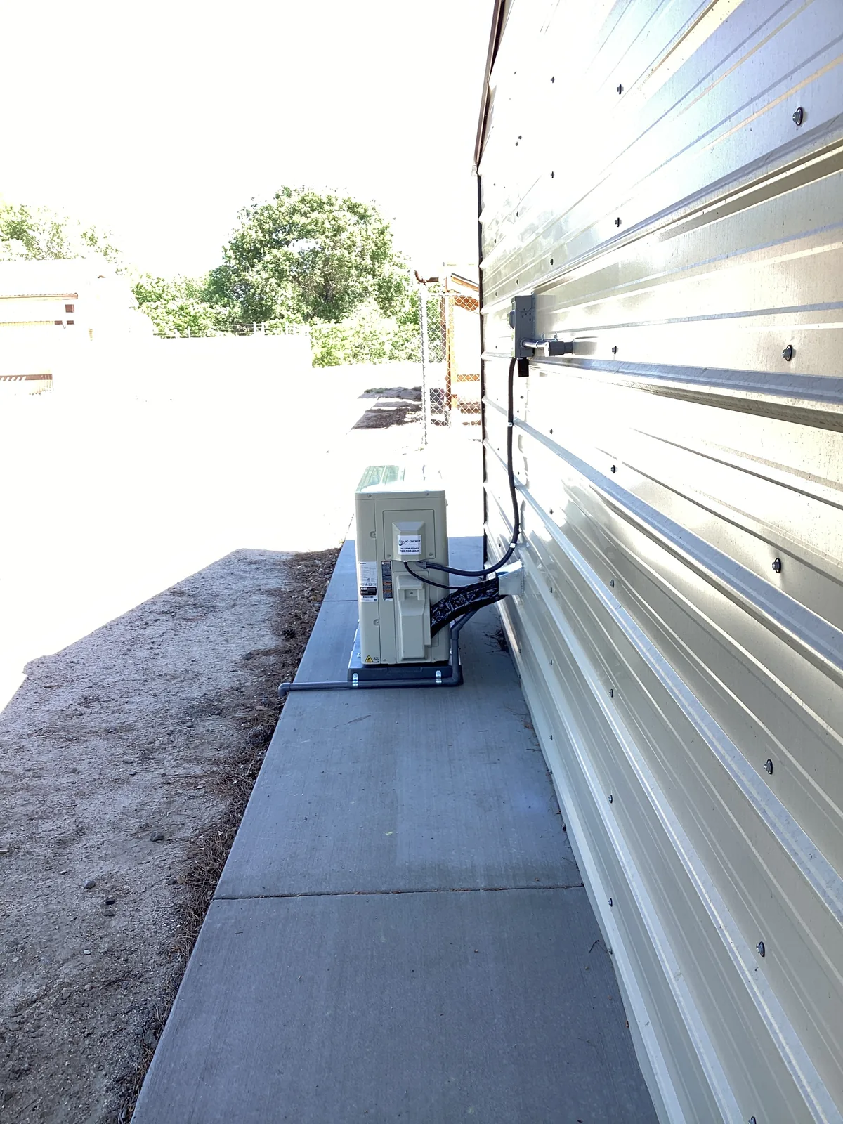 An exterior electrical disconnect and conduit rough-in mounted on a metal building wall with a High Desert backdrop.