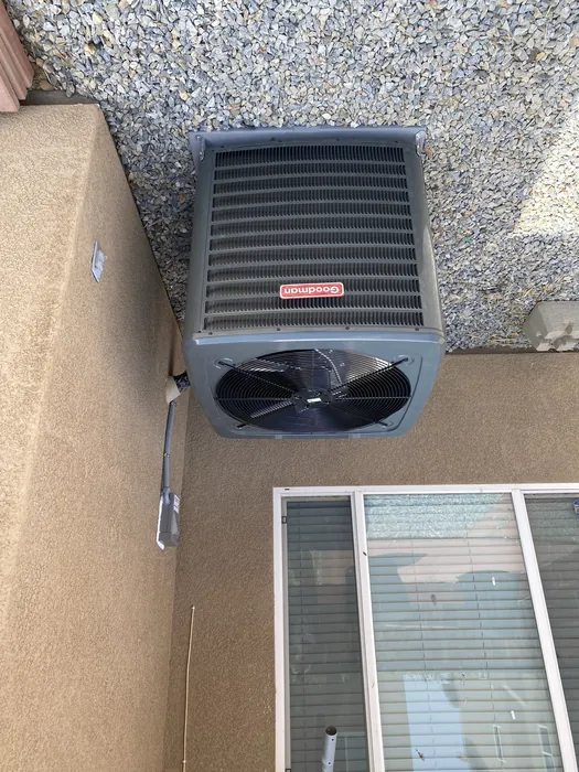 Goodman air conditioning condenser installed on gravel beside a stucco wall at a High Desert home in the Inland Empire.