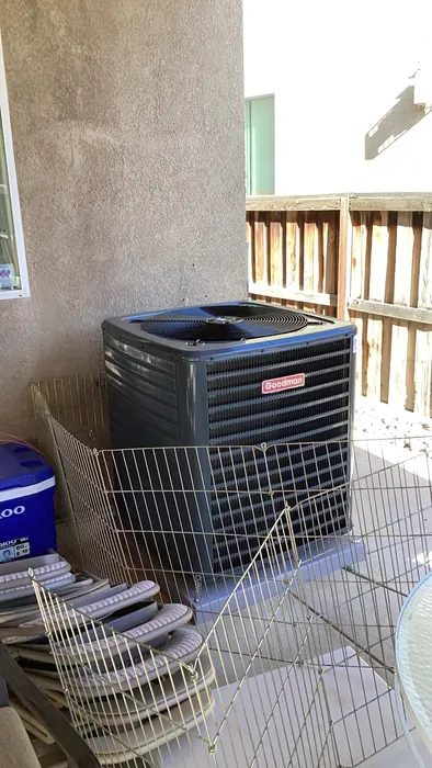 A Goodman gas pack HVAC unit set on a pad beneath a wood patio cover at a High Desert home.