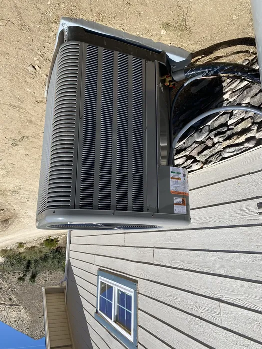 Rear coil of a Rheem condenser unit set on a deck with a High Desert hillside backdrop in the Inland Empire.