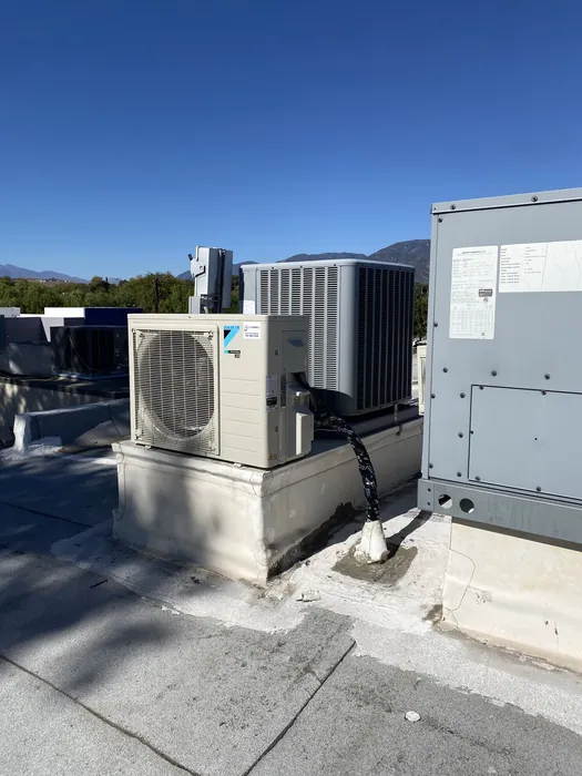 Rooftop air conditioning condenser and Daikin package unit mounted on a flat roof with clear blue High Desert sky overhead.