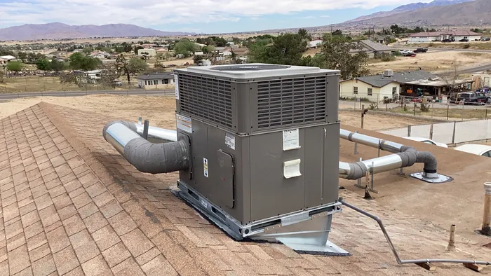 Newly installed rooftop packaged HVAC unit with insulated duct elbows, overlooking the open High Desert valley and distant mountains.