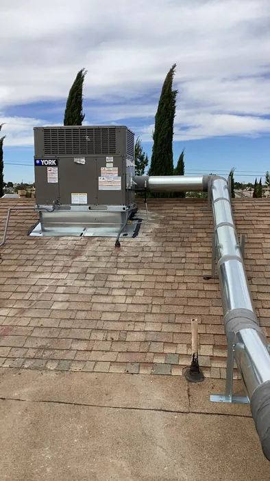 A YORK rooftop packaged gas pack HVAC unit installed with a new galvanized flue vent running across a shingled roof.