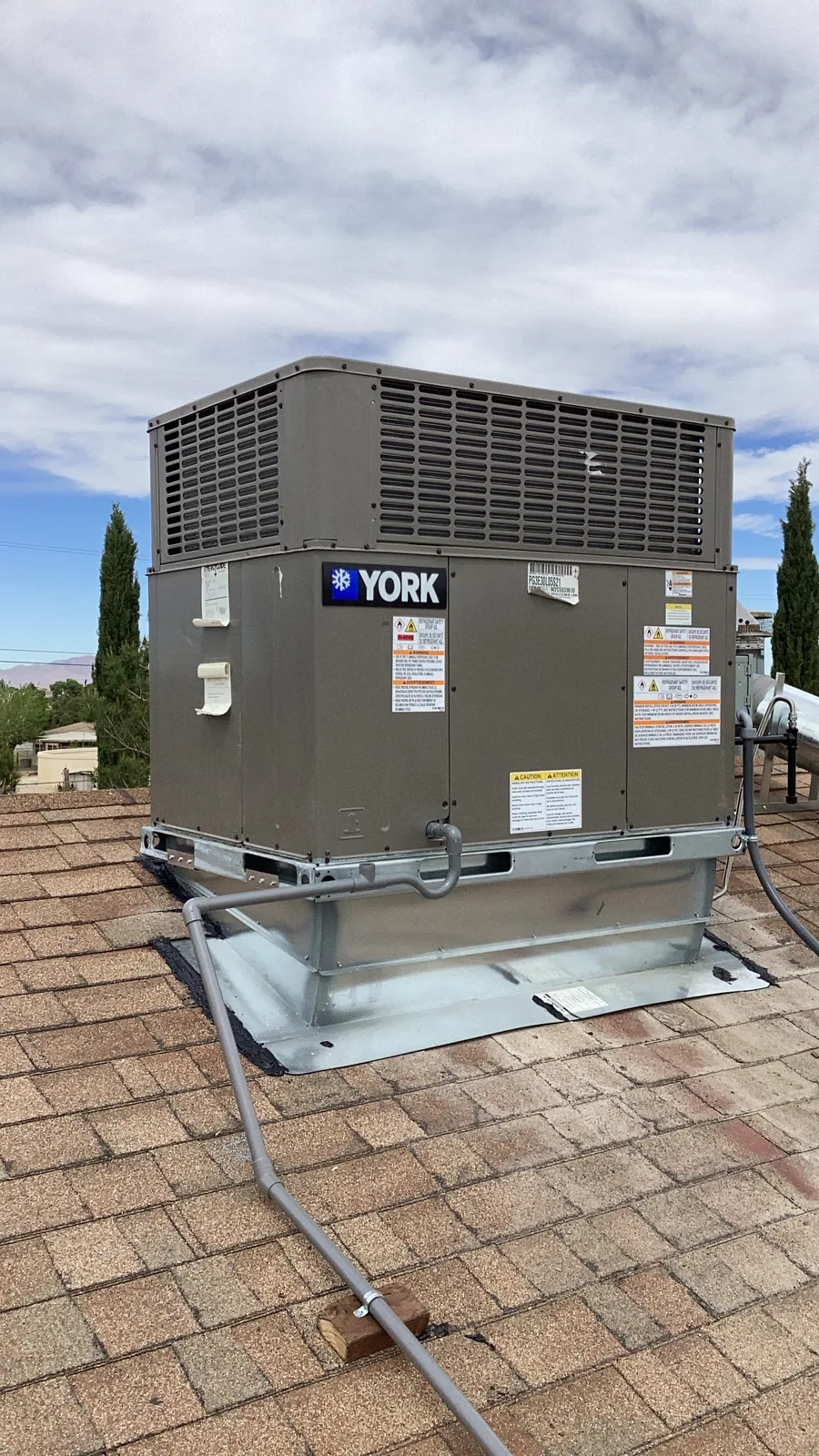 Close-up of a newly installed YORK rooftop packaged HVAC gas pack unit showing the condenser coil grille on a High Desert home.