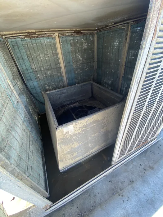 Open rooftop commercial HVAC unit showing interior evaporator coils and blower housing during service or replacement.