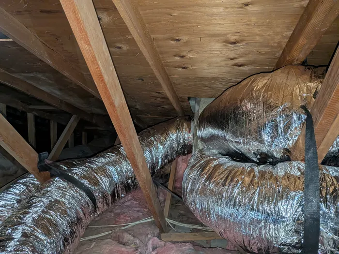 Silver insulated flex duct branch runs routed across attic joists in a High Desert home.