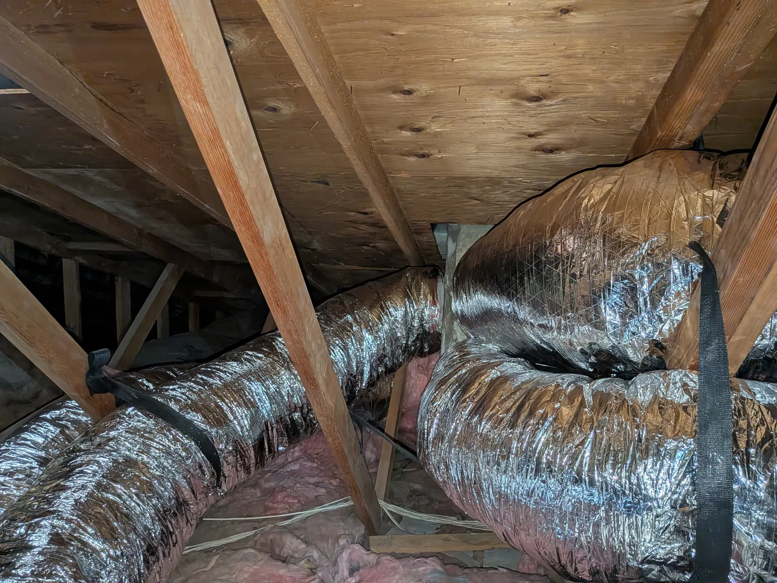 Silver insulated flex duct branch runs routed across attic joists in a High Desert home.