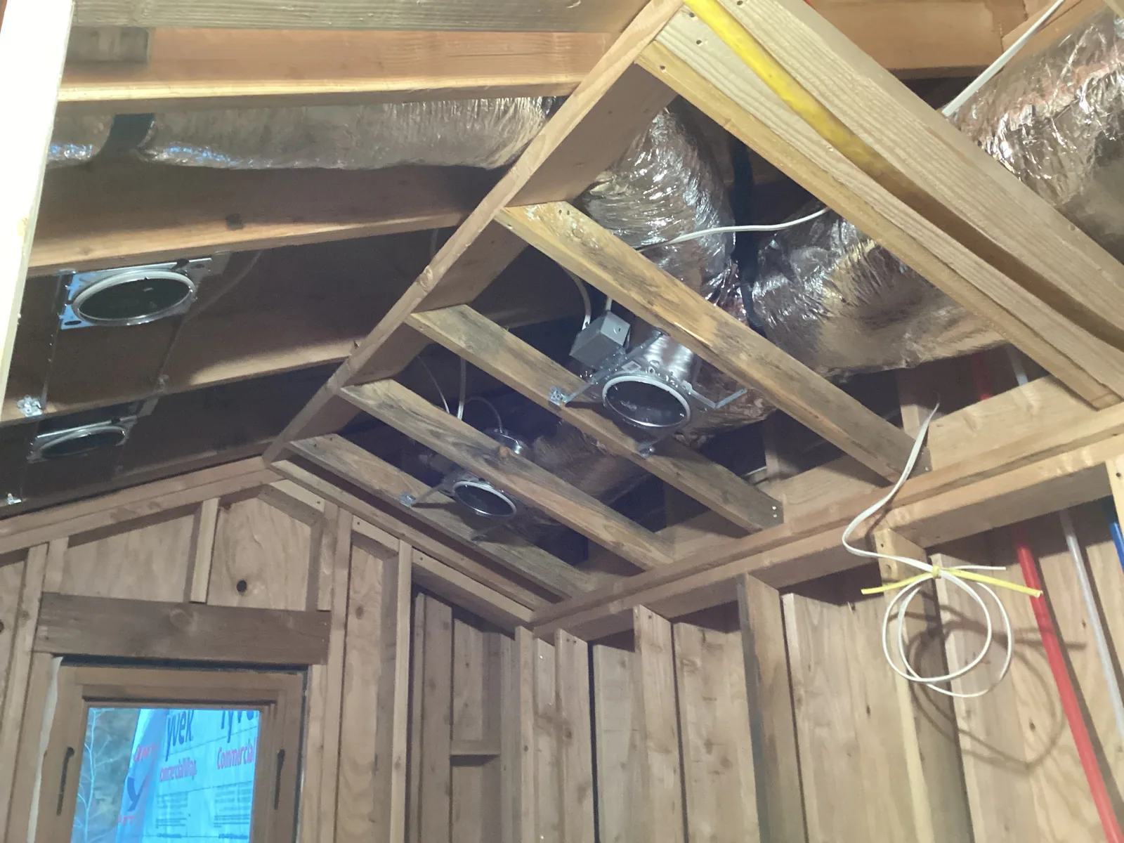 Flexible HVAC ductwork runs and supply register boots installed between attic joists with a balancing damper on a High Desert home.