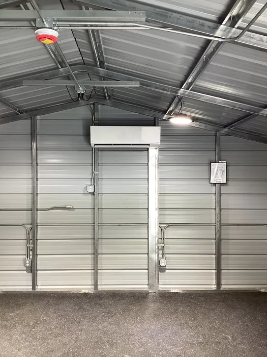 Overhead HVAC piping and air handler rough-in running across the steel framing of a metal commercial building interior.