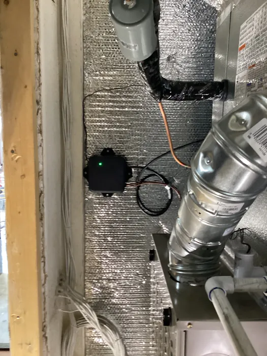Air handler galvanized supply duct with a low voltage control box, orange thermostat wiring, and bundled romex on the floor joist below in a High Desert home