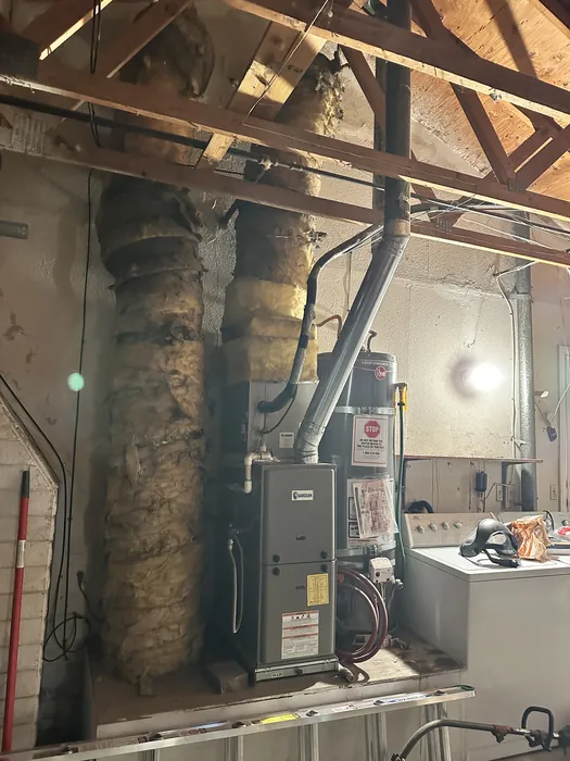 Gas furnace and air handler installed in a residential attic with insulated flex ductwork and a metal flue pipe in an Inland Empire home.