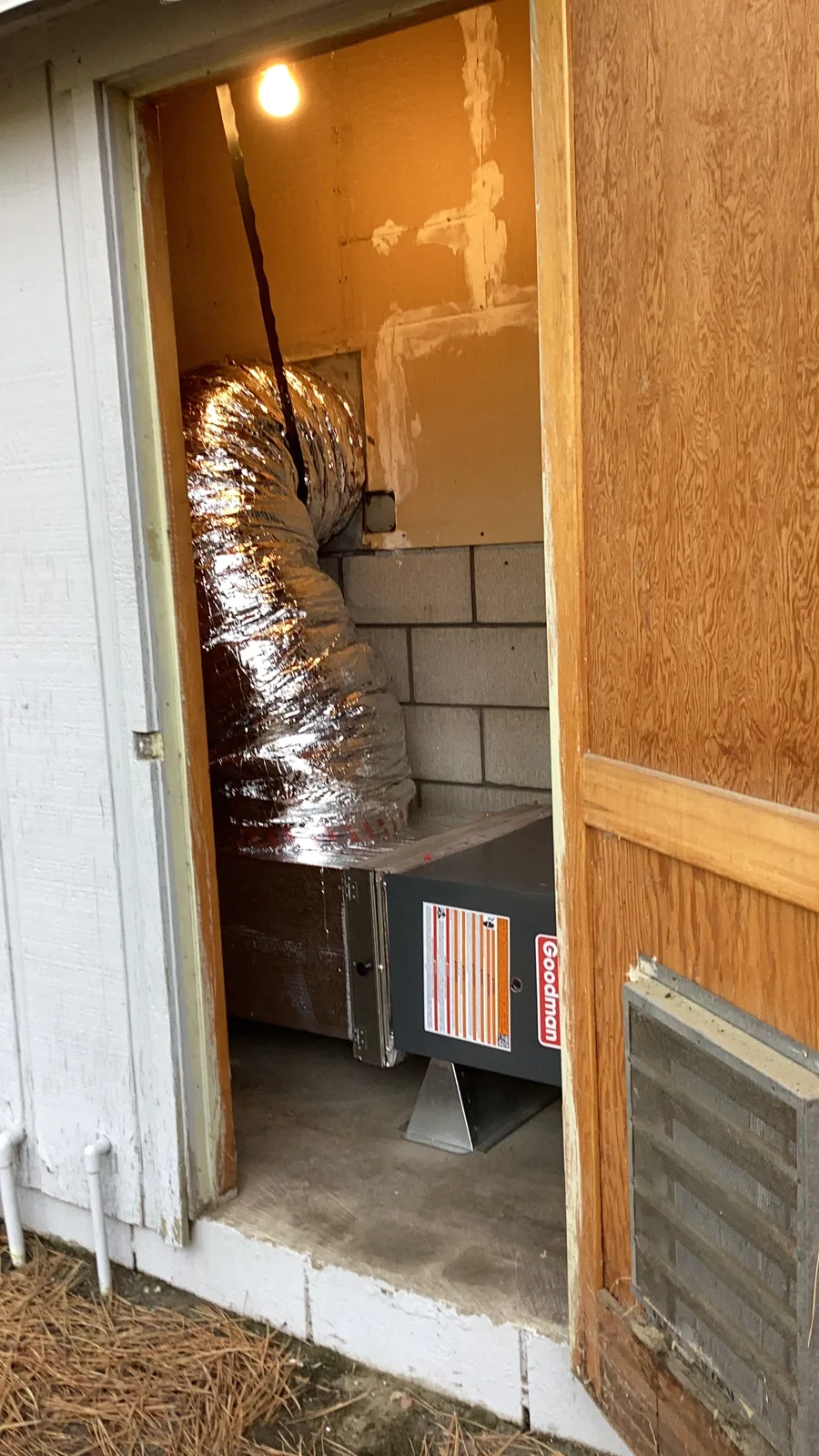 A Goodman furnace connected to insulated flex ductwork inside a tight exterior utility closet on a High Desert property.