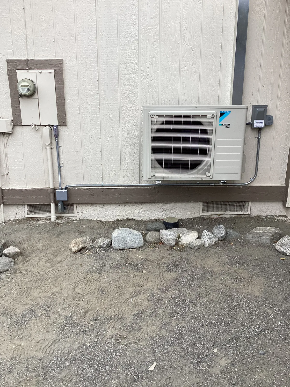 Daikin ductless mini split outdoor condenser mounted on a home wall with refrigerant line set, electrical disconnect, and conduit.