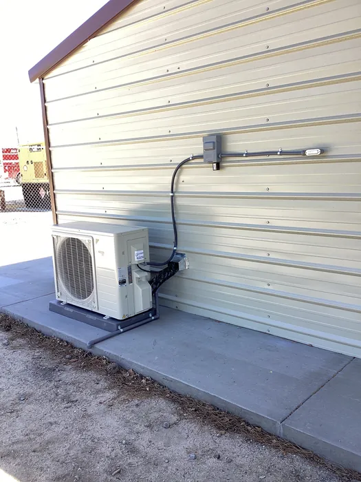 Daikin ductless mini-split condenser mounted on a wall bracket against a metal building exterior in the High Desert.
