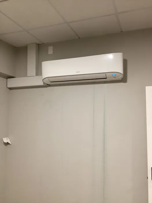 Daikin wall-mounted mini-split air handler head installed high on an interior tiled wall.