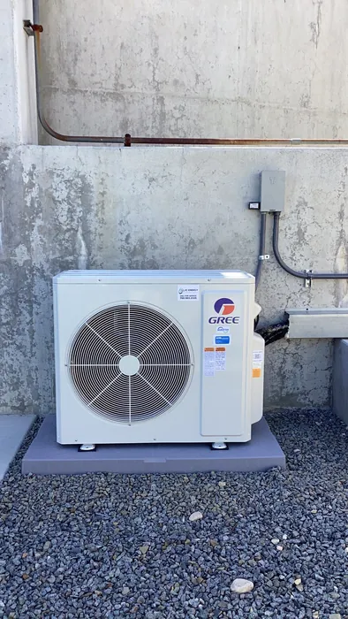 A Gree mini-split outdoor condenser mounted on a concrete wall with copper line set and disconnect box at an Inland Empire job site.