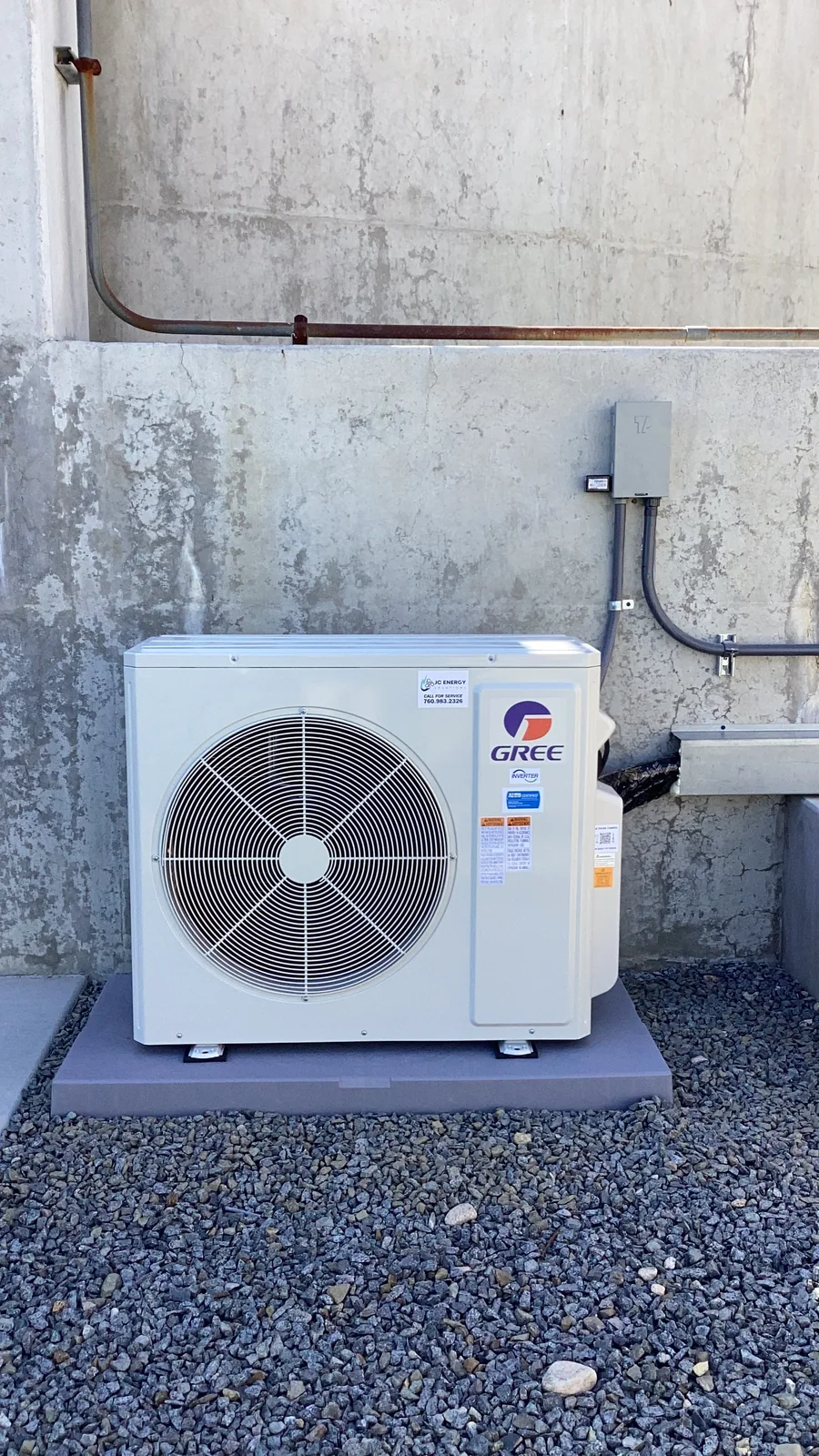 A Gree mini-split outdoor condenser mounted on a concrete wall with copper line set and disconnect box at an Inland Empire job site.