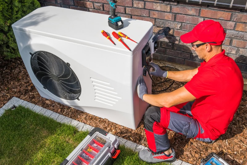 A handyman repairing a heat pump