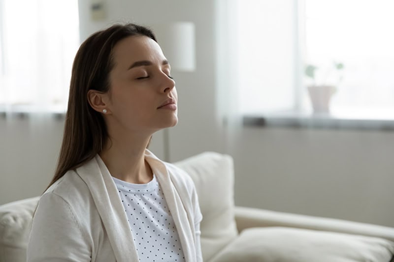 Why Do I Need a Humidifier? A person sitting on the couch breathing in clean air.
